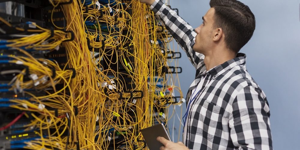 Imagem de um técnico olhando a caixa de emenda óptica de algum estabelecimento.